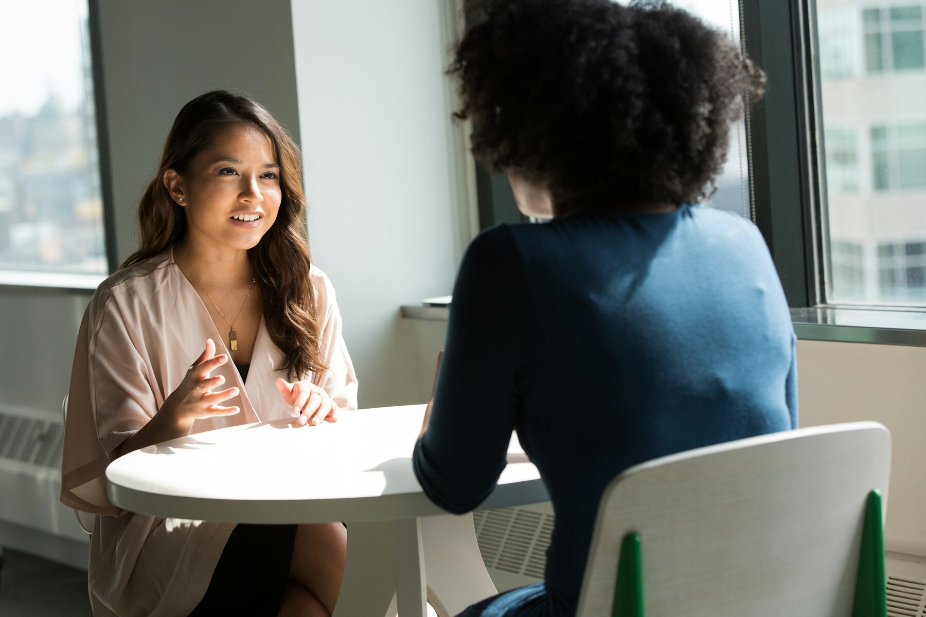 Two professionals in conversation beside a sunlit window