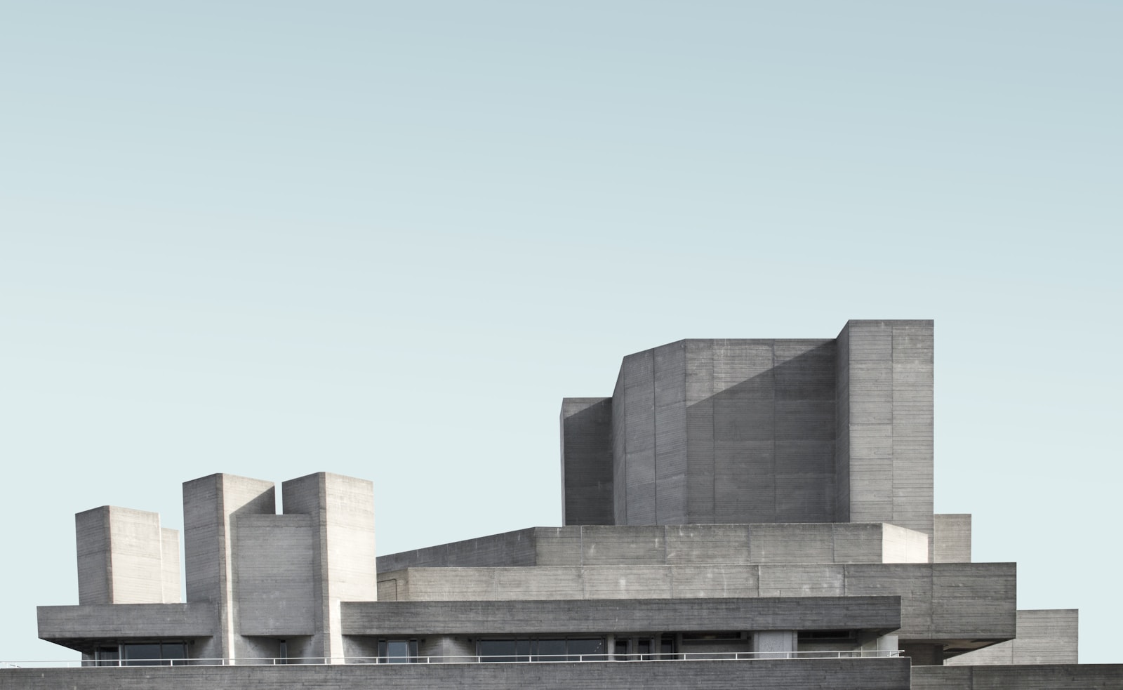 Brutalist concrete building beneath a pale blue sky
