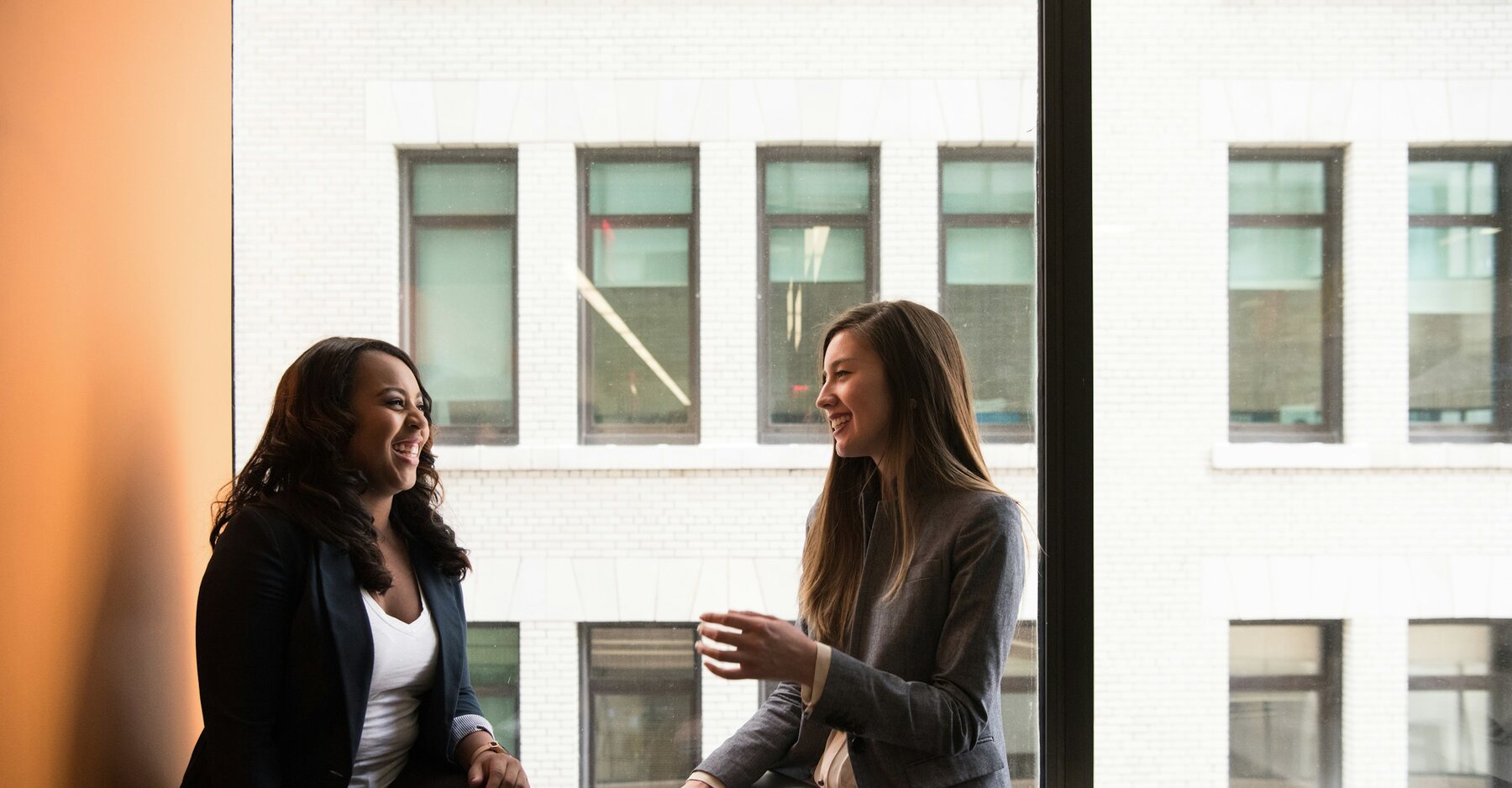 Two professionals sharing a conversation beside a window